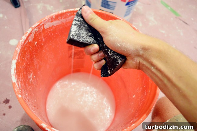 Drywall Taping, Mudding, and Sanding: Step-by-Step Guide 31 squeezing water out of sanding block like a sponge into a bucket