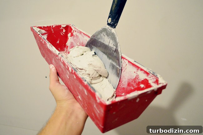 Drywall Taping, Mudding, and Sanding: Step-by-Step Guide 6 joint compound in mud pan with knife