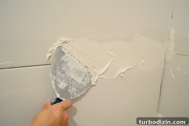 Drywall Taping, Mudding, and Sanding: Step-by-Step Guide 10 applying thick layer of drywall mud as bed across drywall seams