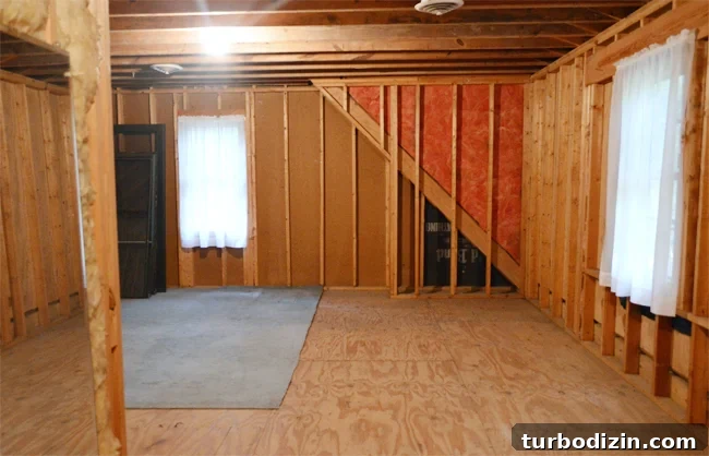 How We Transformed Our Bonus Room Into a Stylish Lounge 17 Unfinished attic storage room with exposed studs and curtained windows