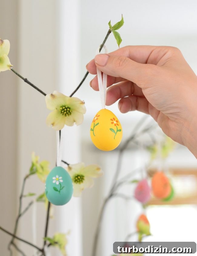 How to Make a Charming DIY Easter Egg Tree for Spring Decor 5 placing decorative painted egg on Easter Tree