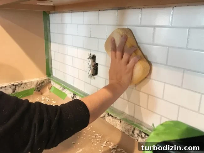 Install a Subway Tile Kitchen Backsplash for $200 DIY Guide 15 Sherry wiping grout smooth on kitchen backsplash using a damp sponge