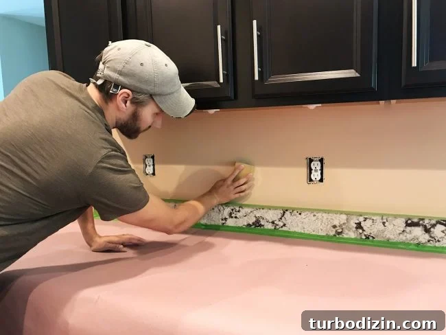 Install a Subway Tile Kitchen Backsplash for $200 DIY Guide 6 John sanding backsplash wall in preparation for tile installation