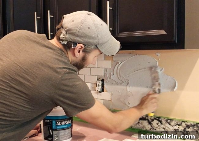 Install a Subway Tile Kitchen Backsplash for $200 DIY Guide 8 John spreading mastic adhesive on backsplash wall in kitchen