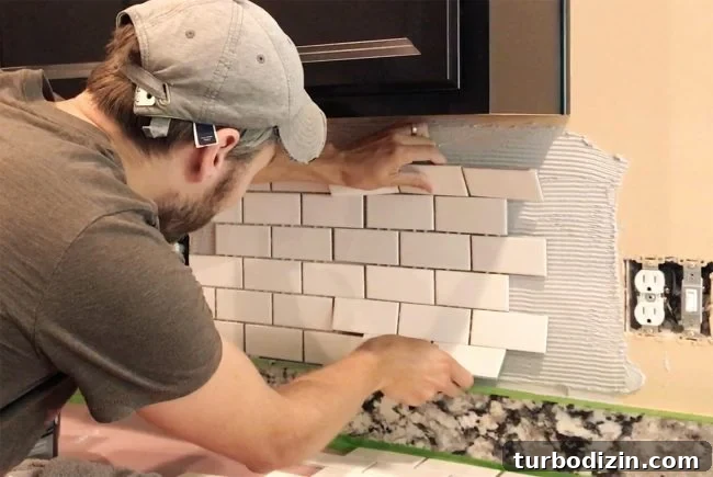 Install a Subway Tile Kitchen Backsplash for $200 DIY Guide 9 John placing white subway tile sheet onto mastic to set backsplash