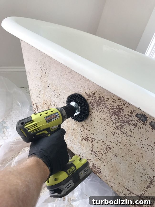 Sanding attachment on drill buffing the outside of old clawfoot tub