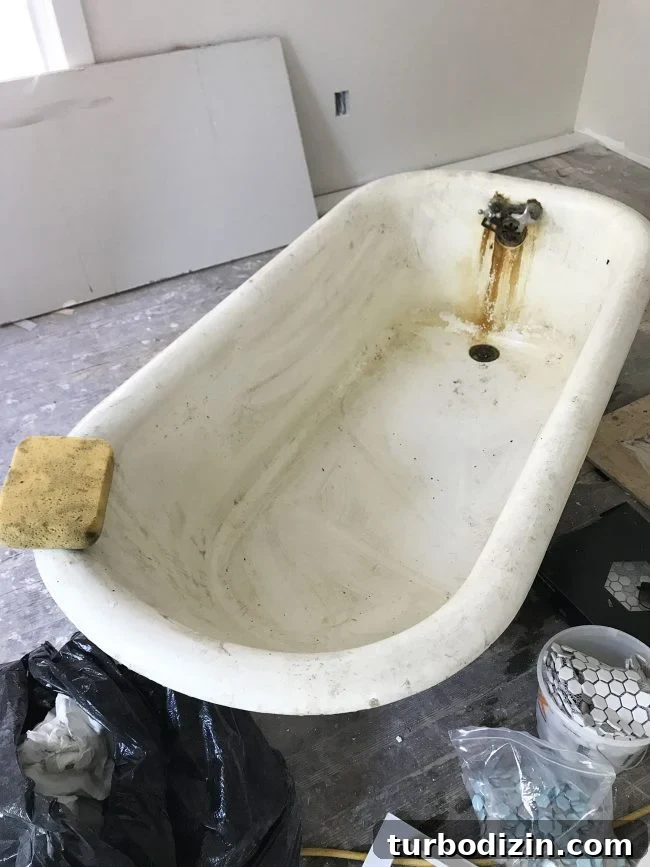 Dirty inside of old clawfoot tub with sponge