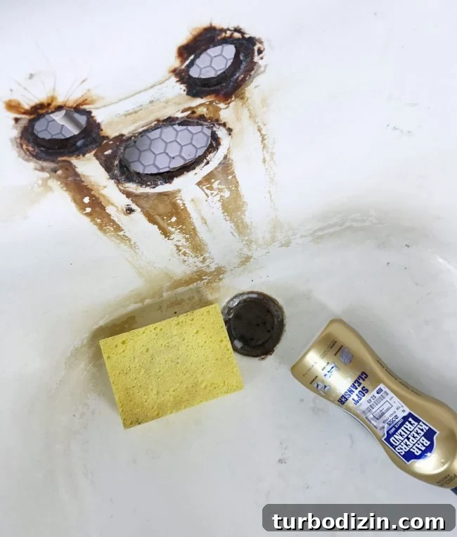 Sponge and bar keepers friend cleanser in rust stained clawfoot tub