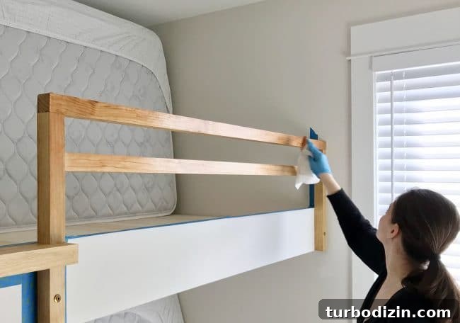 DIY Guide: Building Custom Built-In Bunk Beds for Your Home 21 Sherry applying stain to bunk bed railing for raw wood look