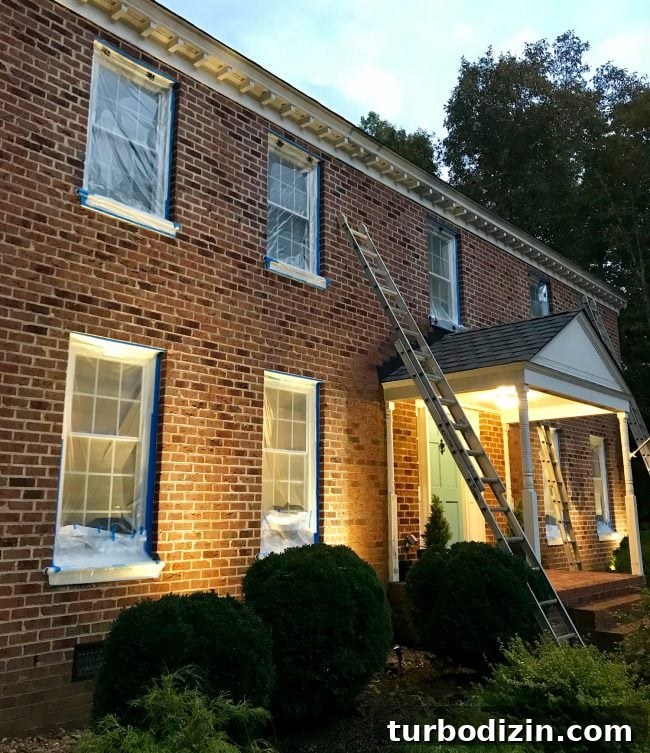 brick house prepped for painting with windows taped up