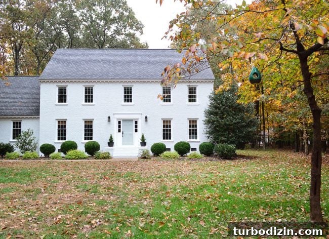 white painted brick house with fall leave and tranquility blue door