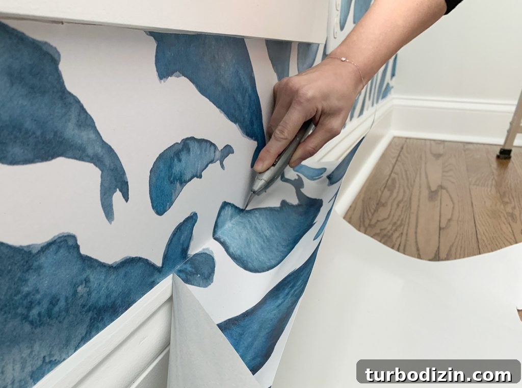 Cutting Off Excess Peel-And-Stick Wallpaper Along Baseboard