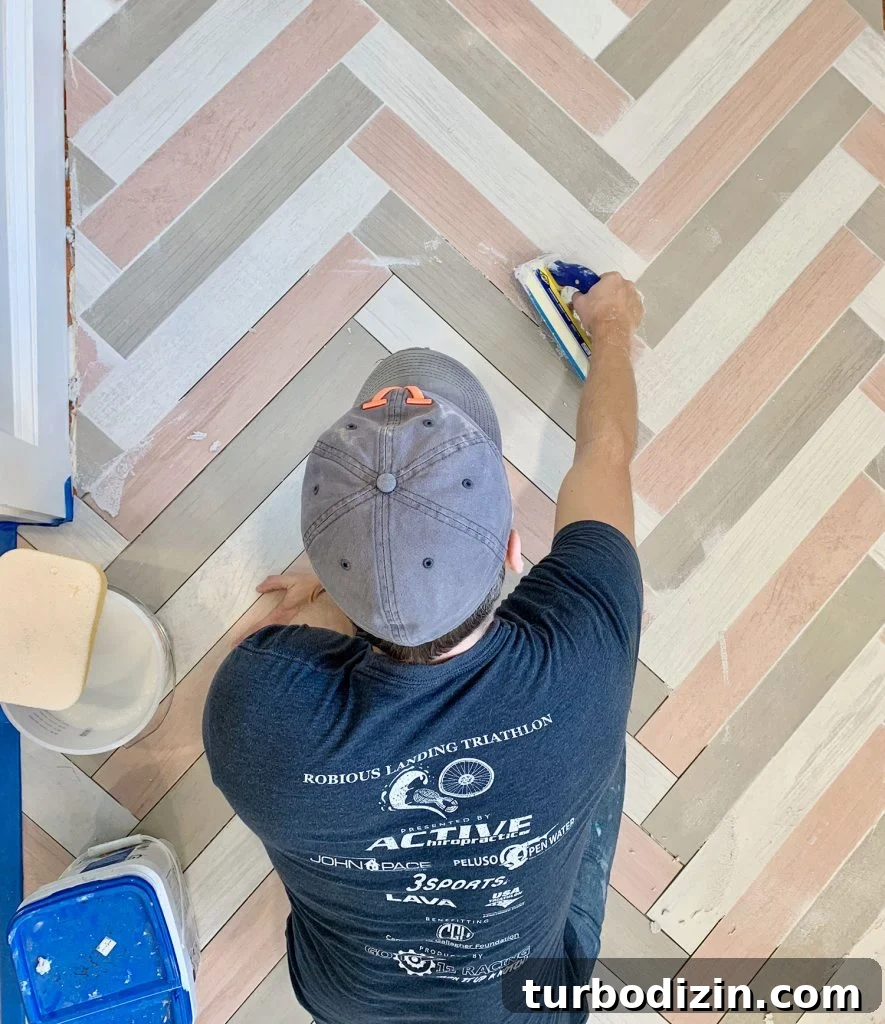 John grouting a colorful herringbone mudroom floor with mapei grout