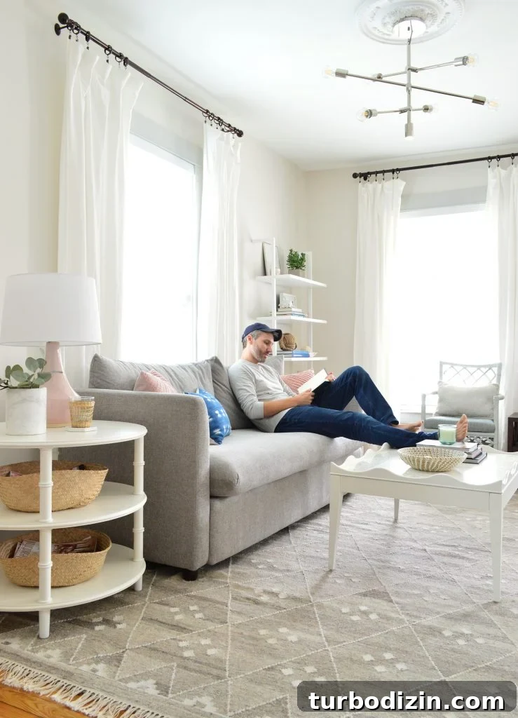 Bright, Airy Living Room Ideas That Stay Comfortable and Practical 11 John reading on gray sofa with feet on scalloped white coffee table