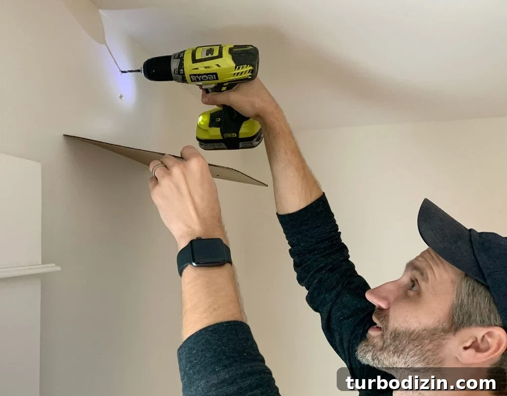 Drilling larger holes for curtain rod using cardboard to catch dust