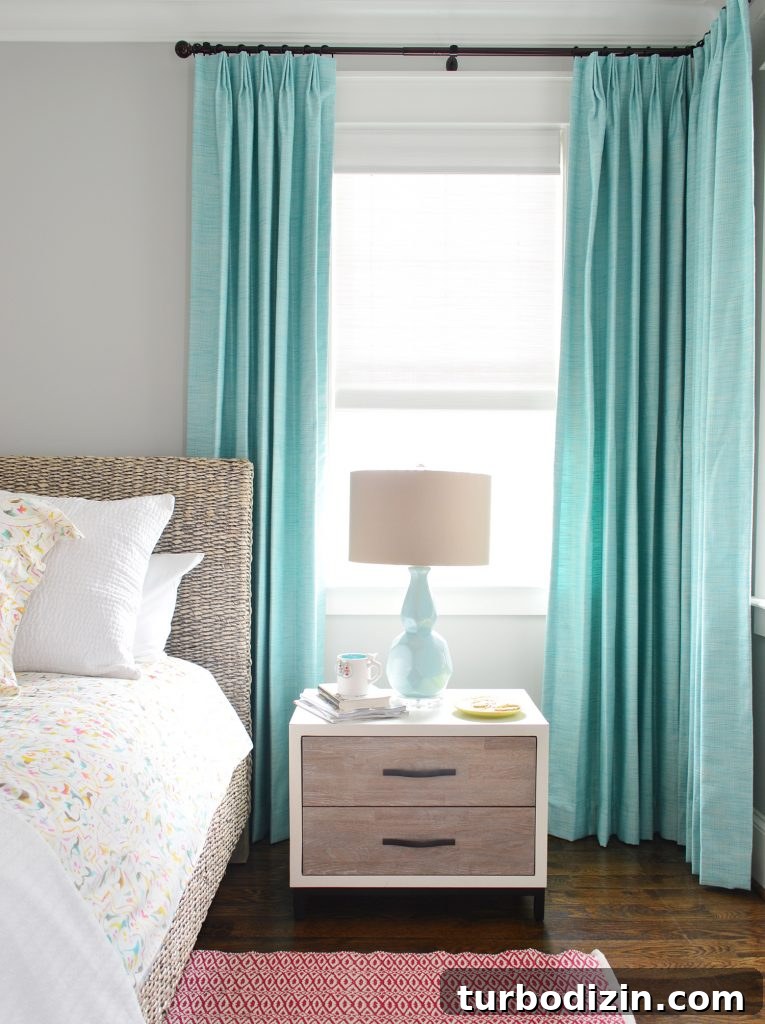Blue aqua curtains hanging in bedroom behind nightstand