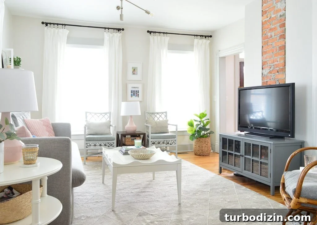 Beach house living room with exposed brick fireplace and two windows with floor to ceiling white curtains