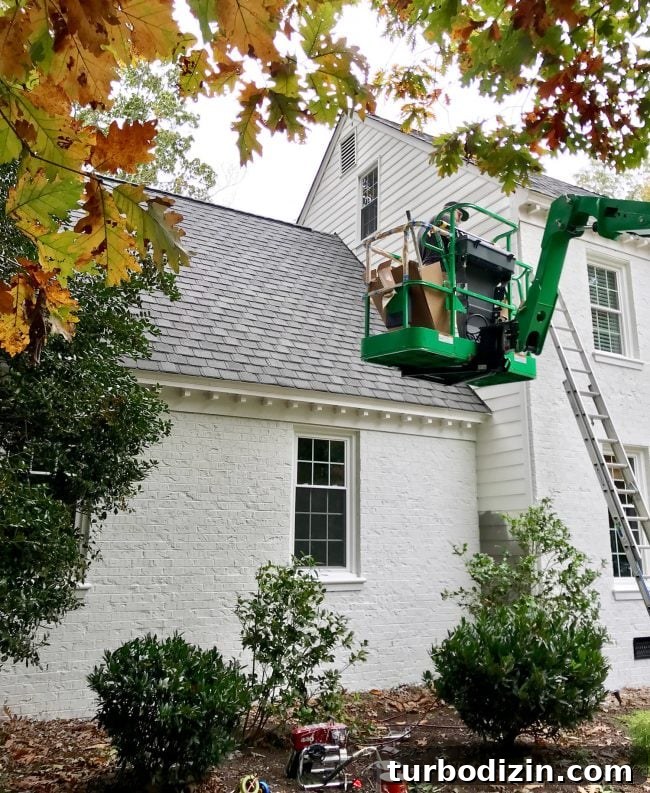 What to Know Before Painting Your Brick House 8 painter in crane painting siding of a brick house white
