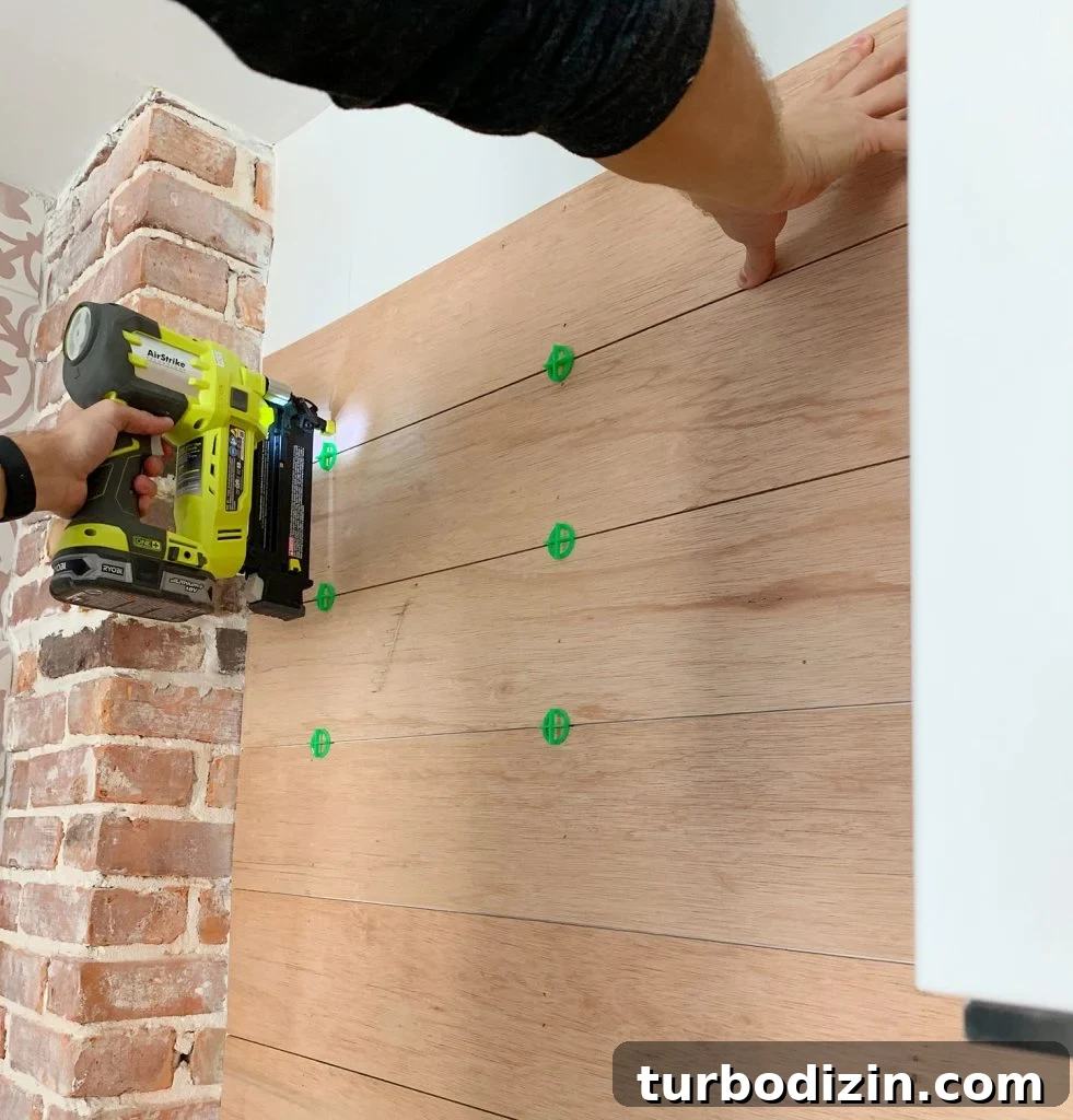 DIY Shiplap Wall Plank Makeover for $31 Total 19 Nail Gun Securing Wood Panels To Backsplash Using Tile Spacers