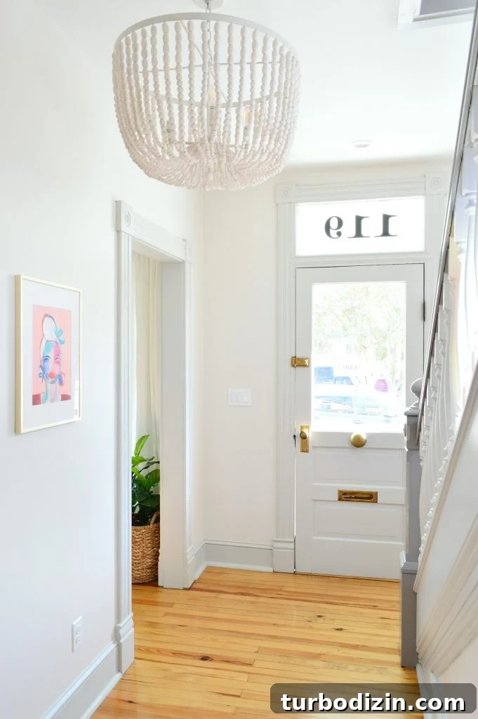 Beaded Chandelier In Beach House Foyer With Glass Front Door And Pink Art