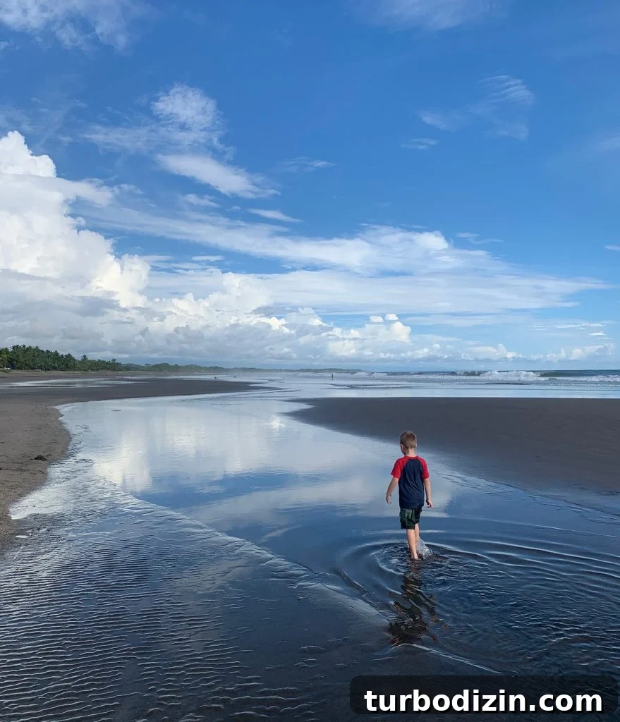 Young Boy Playing In Tide Pool at Esterillos Oeste Beach In Costa Rica