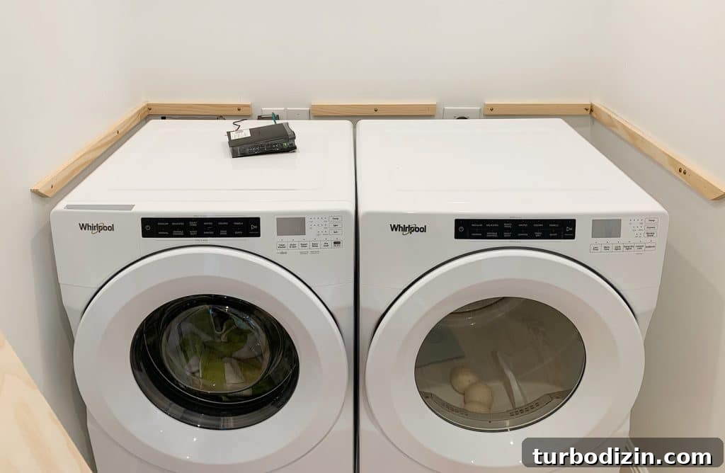 Wood laundry shelf supports added to walls besides washer and dryer