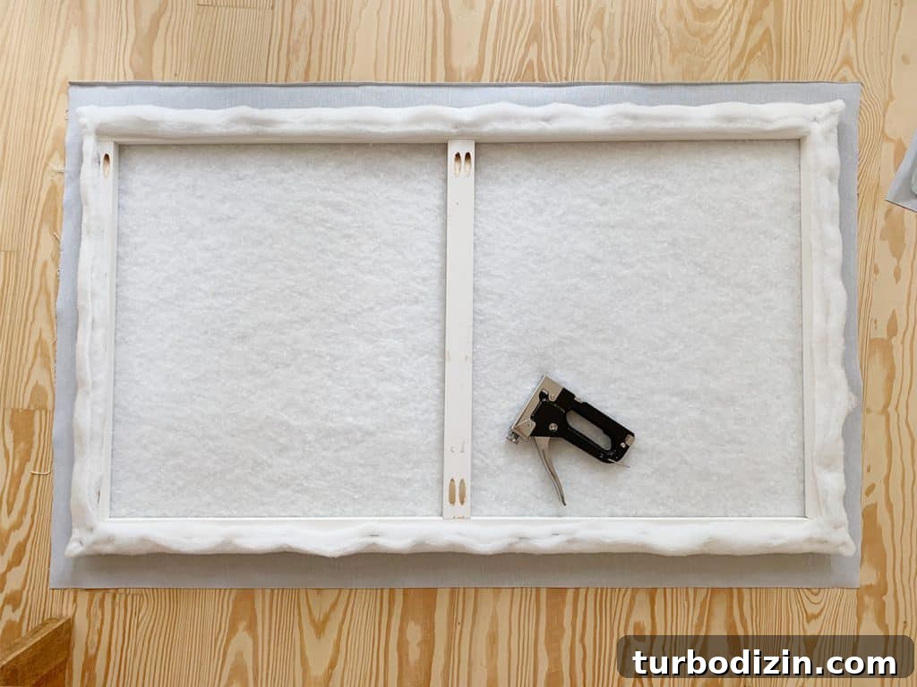 Simple DIY Headboard Ideas to Build Yourself in a Weekend 11 Batting covered wood frame laid on floor atop fabric prior to stapling