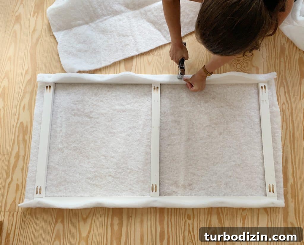 Simple DIY Headboard Ideas to Build Yourself in a Weekend 8 Sherry stapling fabric batting around wood frame for DIY upholstered headboard