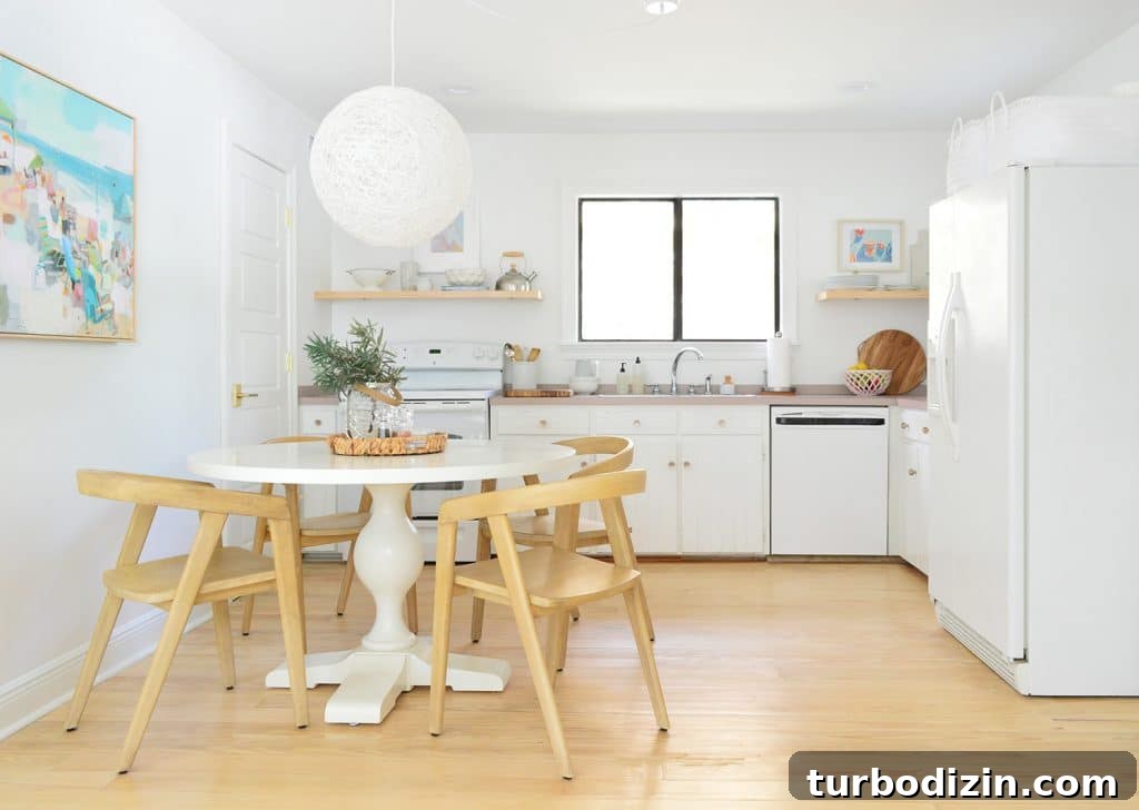 5 Quick Kitchen Updates to Transform Your Space 3 Minimal Kitchen With White Cabinets Pedestal Table And Globe Pendant Light With Wood Chairs