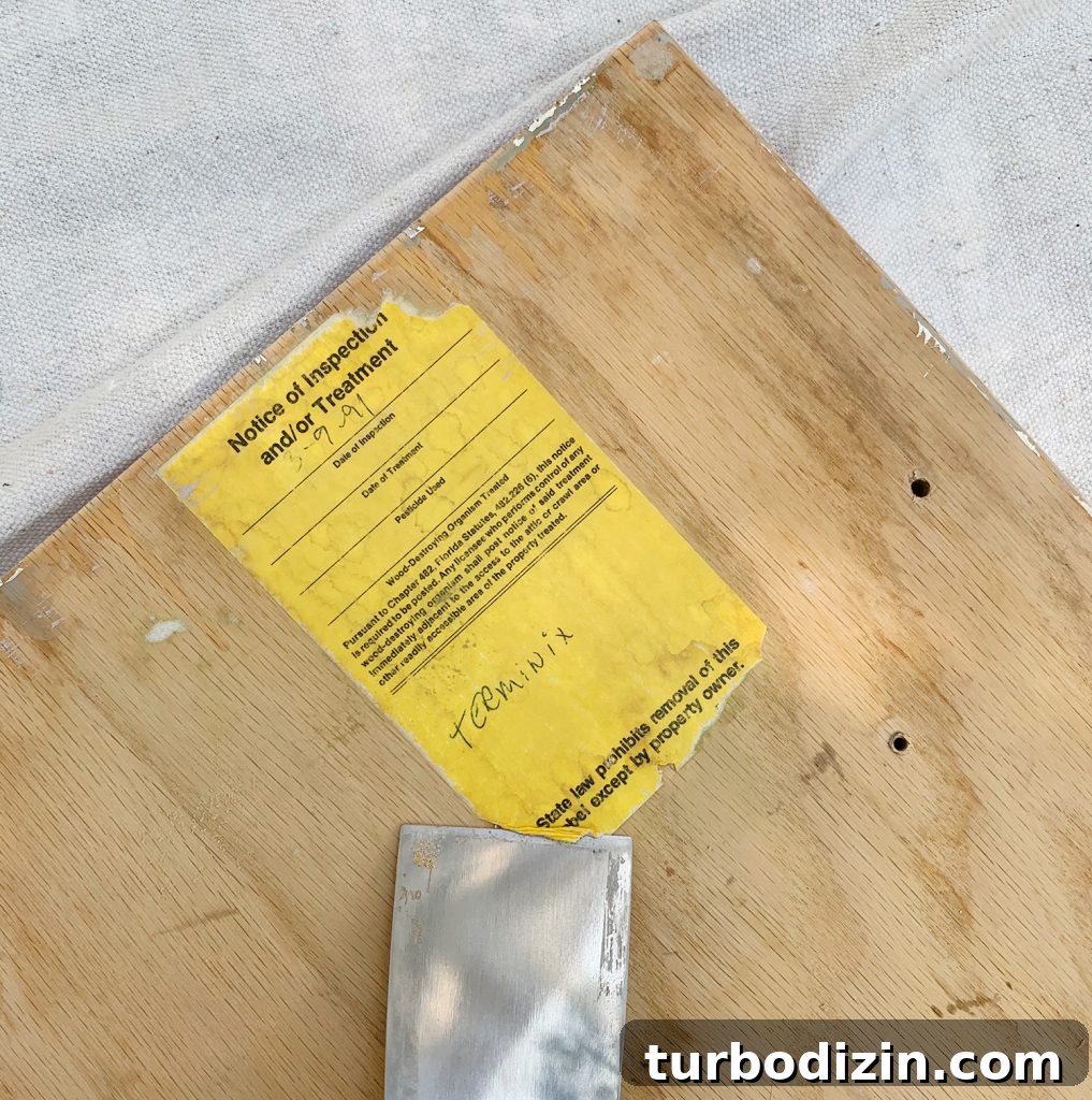 How We Painted Our Kitchen Cabinets Pink: A Room-by-Room Reveal 11 Scraping old label off the back of kitchen cabinets as painting prep