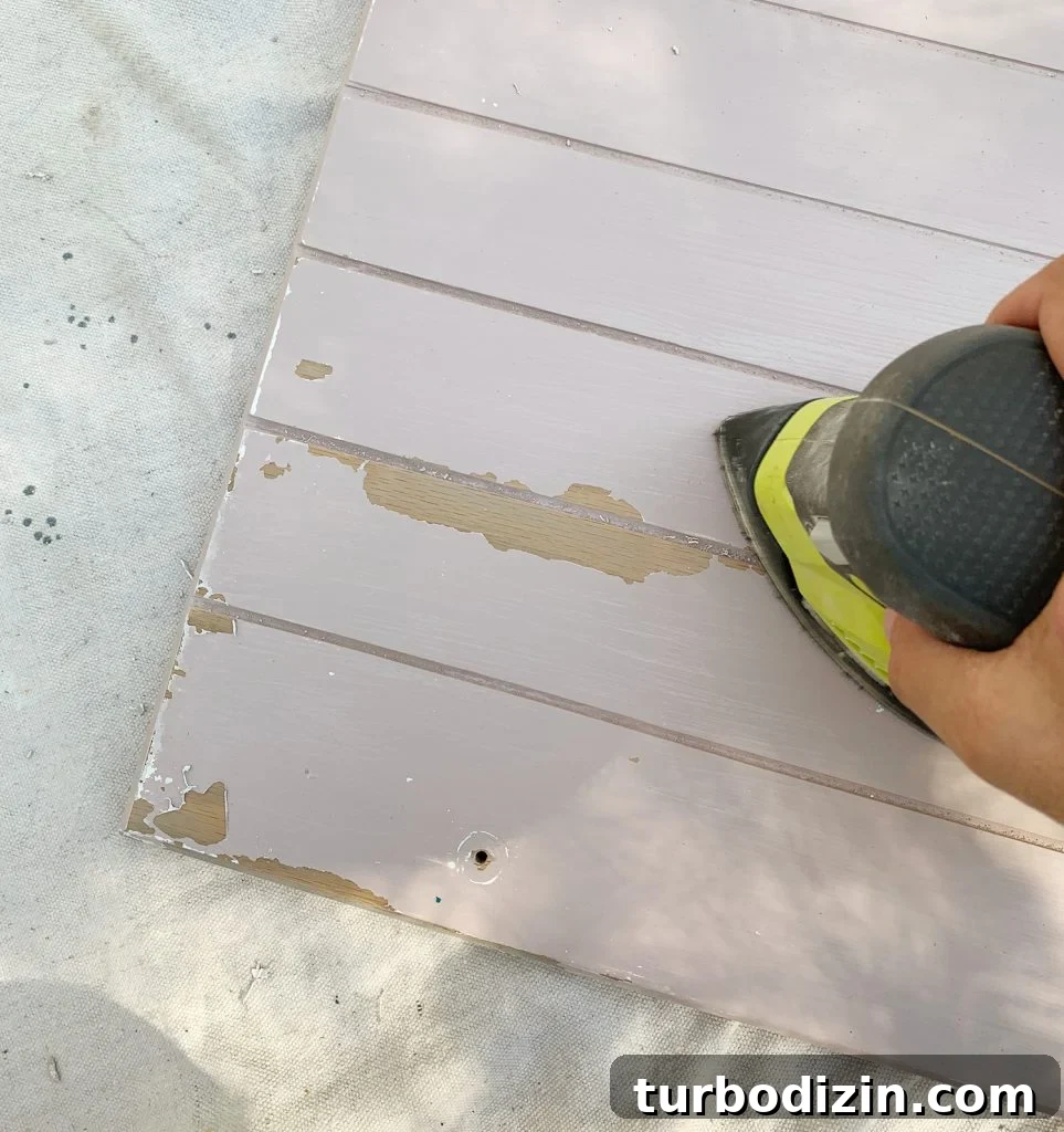 How We Painted Our Kitchen Cabinets Pink: A Room-by-Room Reveal 12 Sanding old paint drips off of wood cabinets in preparation for cabinet painting