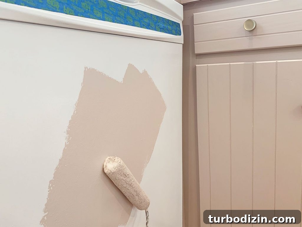 How We Painted Our Kitchen Cabinets Pink: A Room-by-Room Reveal 20 Rolling mauve paint onto white dishwasher using small foam roller