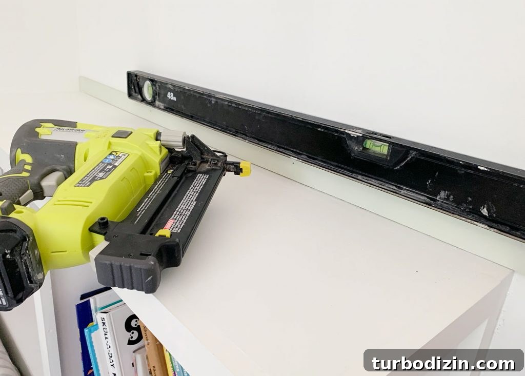 How to Create a Colorful Wood Accent Wall: DIY Guide 11 Nail Gun Next To First Strip Of Wood Lattice Attached To Wall With Level