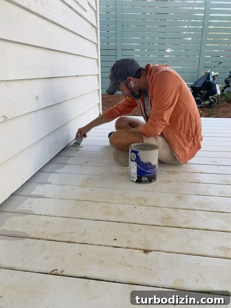 John edging porch floor with gray floor paint on paintbrush 