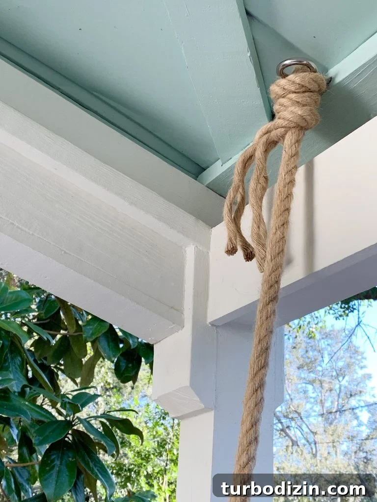 How to Hang an Outdoor Daybed: Step-by-Step Video Guide 6 Rope knotted around screw eye hook in ceiling of covered porch