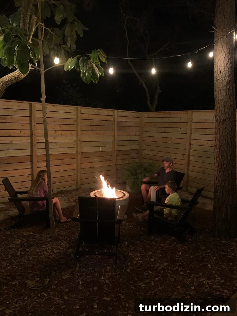 Family sitting around fire pit with unpainted fence