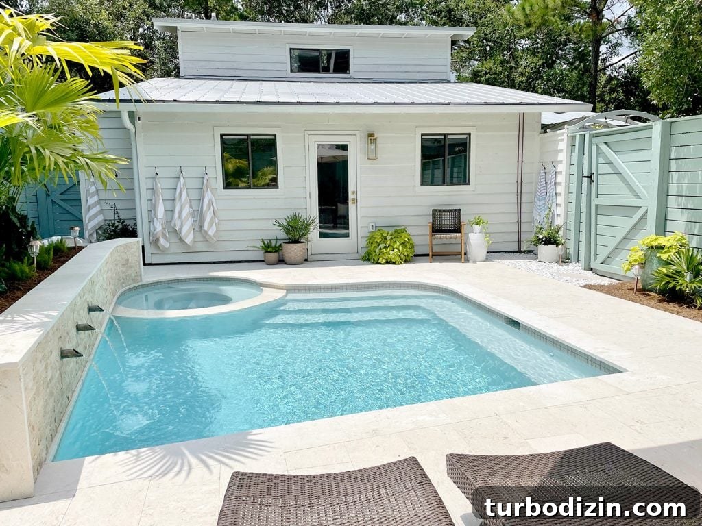Small freeform pool with white house metal roof in background