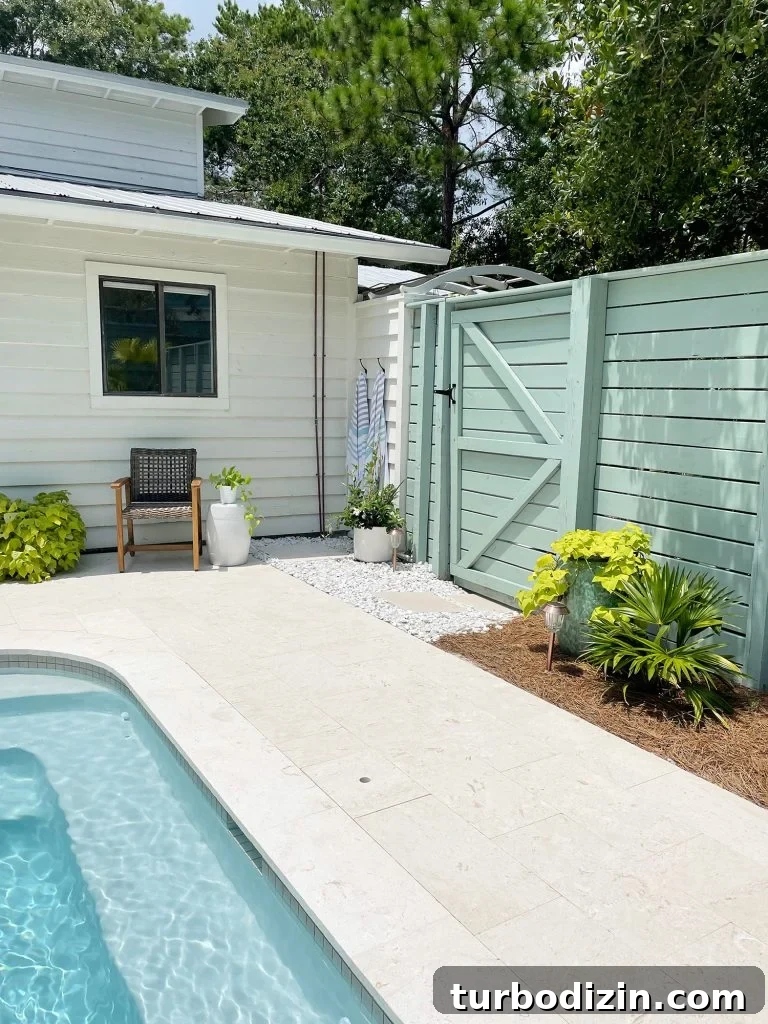 Horizontal slat gray green wood fence around pool area with gate near house
