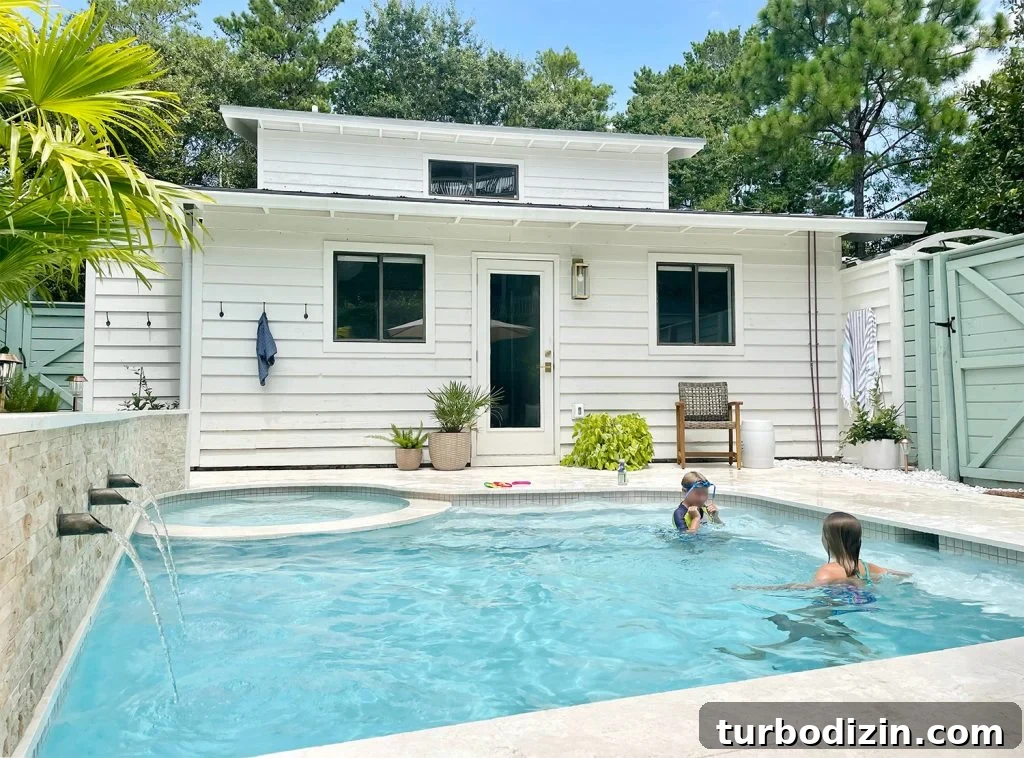Two kids playing in small freeform pool with scupper fountains on wall