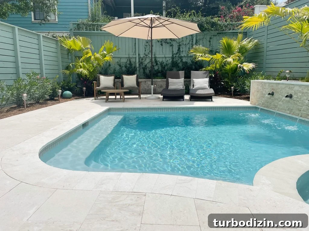 Curved edge pool with seating area in the background with green fences