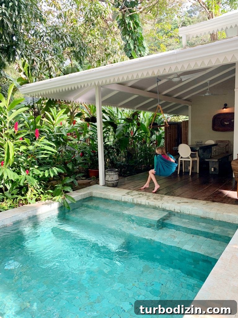 Inspiration photo of small tropical pool next to white house and child in swing